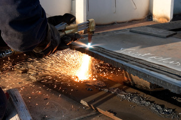worker inside factory cut metal using blowtorch