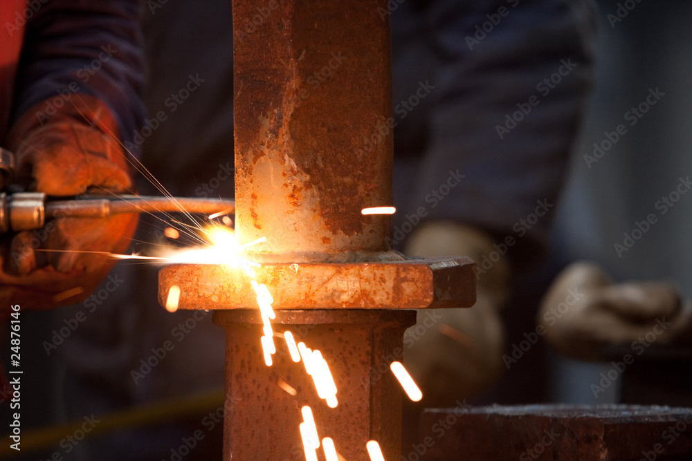 Wall mural worker inside factory cut metal using blowtorch