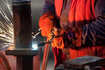 worker inside factory cut metal using blowtorch