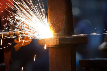 worker inside factory cut metal using blowtorch
