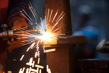 worker inside factory cut metal using blowtorch