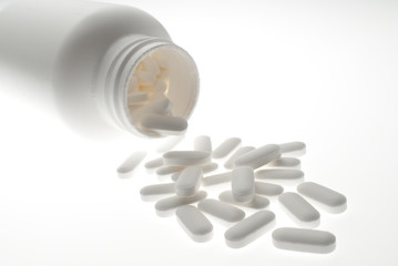 Close up of white bottle and pills