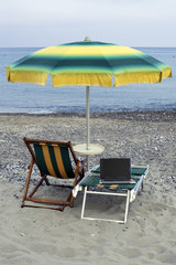 Beach umbrella and deckchair with a laptop on