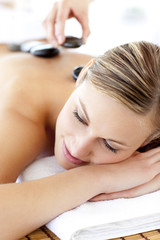 Obraz na płótnie Canvas Charming young woman enjoying a back massage with hot stone
