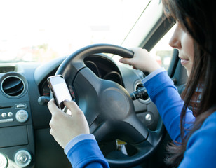 Beautiful brunette woman using her cellphone while driving