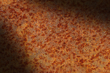 Rusted corroded metal surface diagonally lit.