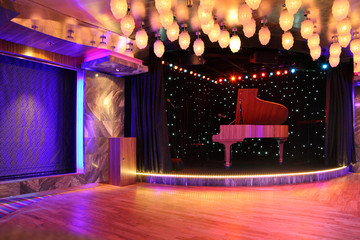 grand piano on empty stage with wooden floor and many decor lamp