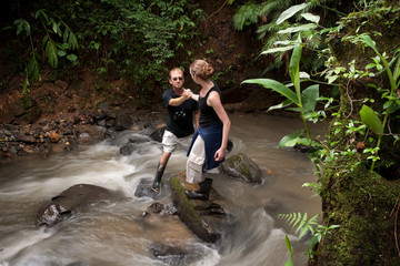 Woman helping man cross Costa Rican river