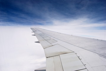 Blick auf Flugzeugflügel in der Luft über den Wolken