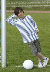 Junge mit Fussball, lächelnd , am Tor angelehnt