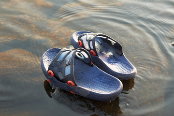 Man’s flip flops on stone in water