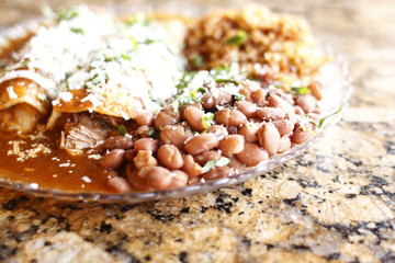 A plate of gourmet enchiladas with rice and beans.