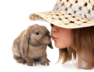 Girl in a straw hat kisses dwarf rabbit.