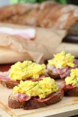 Sandwiches with scrambled eggs and bacon, garnished with chives