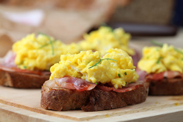 Sandwiches with scrambled eggs and bacon, garnished with chives