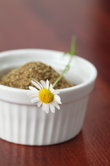 Chamomile flower on a white bowl with dry chamomile tea