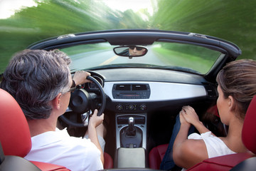 Man and woman driving convertible