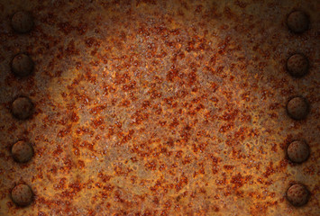 Rusted metal surface with rivets dramatically lit