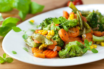 Roasted vegetables with herbs on wooden kitchen table