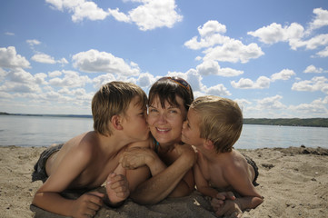 Fototapeta na wymiar Kids kiss mom in the sunshine
