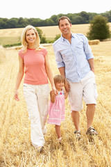 Family Walking Together Through Summer Harvested Field