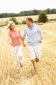 Couple Running Together Through Summer Harvested Field