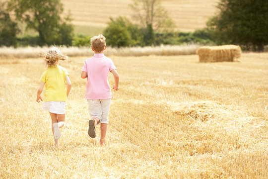 Children Running Through Summer Harvested Field