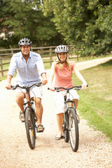 Obraz premium Couple Cycling In Countryside Wearing Safety Helmets