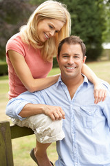 Obraz premium Couple Relaxing In Countryside Sitting On Fence