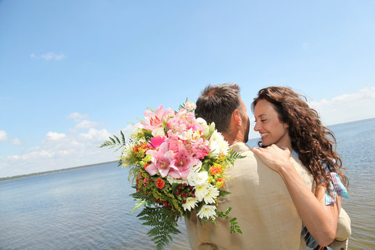 Man Surprising Woman With Bunch Of Flowers