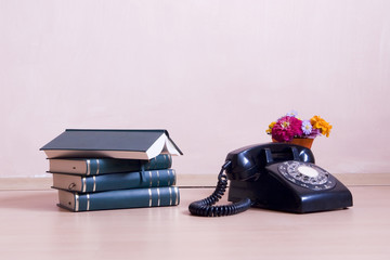 stack of books with vintage telephone and flowers