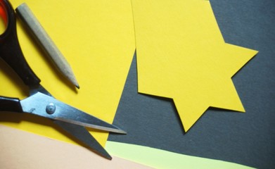 gelber Stern auf braunem Papier, Schere, Stift