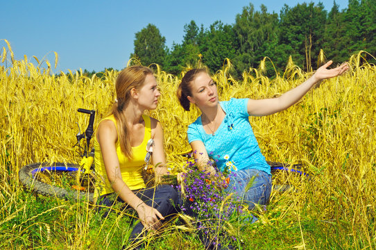 Two pretty girls enjoy the sight in golden field