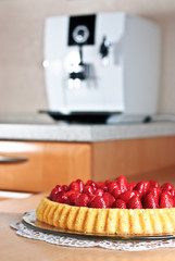 Erdbeerkuchen mit Kaffevollautomat im Hintergrund