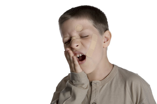 Young boy with band aids on face and hurting, studio shot