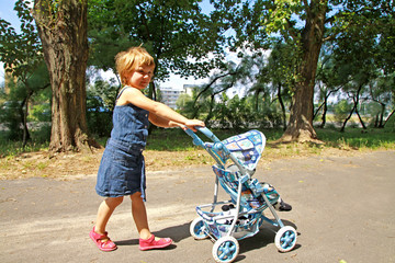 A little girl with toy carriage - obrazy, fototapety, plakaty