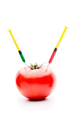 Syringe Injecting Red and Green Liquid Into a Red Tomato