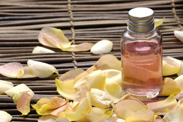 bottles of cosmetic oil  and dry rose petals
