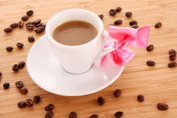 Small white cup of coffee with coffee grain on brown background