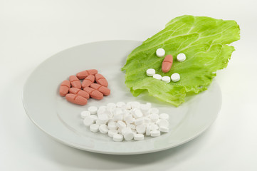 große Portion Vitaminpillen mit smiley und Salatblatt