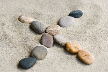 Fototapeta na wymiar lettre X en galets zen dans le sable