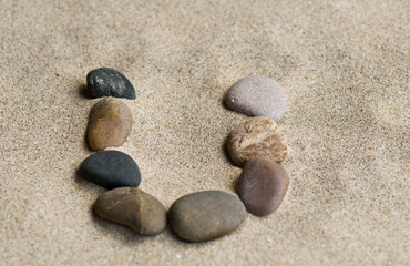 Fototapeta na wymiar lettre U en galets zen dans le sable