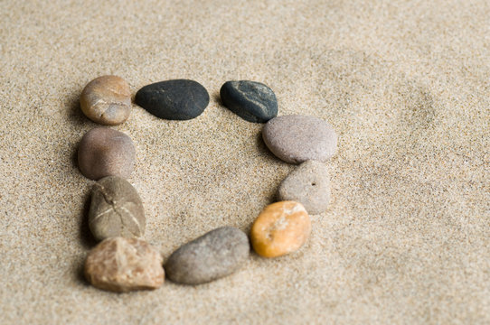 lettre D en galets zen dans le sable