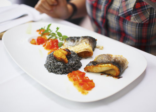 Fish fillet with black risotto and tomato relish