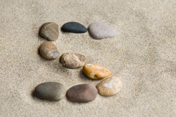Fototapeta na wymiar lettre S en galets zen dans le sable