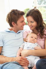 Parents Cuddling Newborn Baby Boy At Home