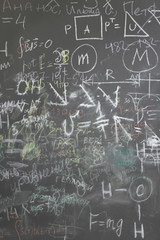 grey school chalkboard with many different formuls, signs and co