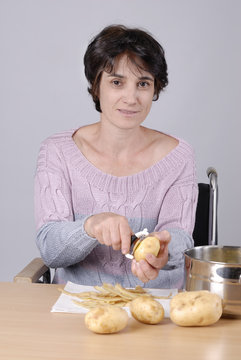 femme handicapé dans chaise roulante pelant des pommes de terre