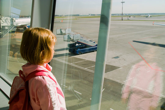 The girl looks out of the window the airport on an airfield