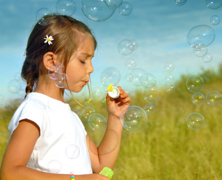 Sumer wishes, little girl blowing soap bubbles at sunset - Powered by Adobe
